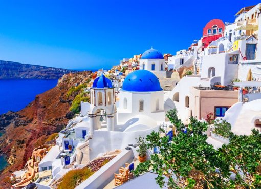 “Sunset view of white buildings and blue-domed churches in Oia, Santorini, Greece”